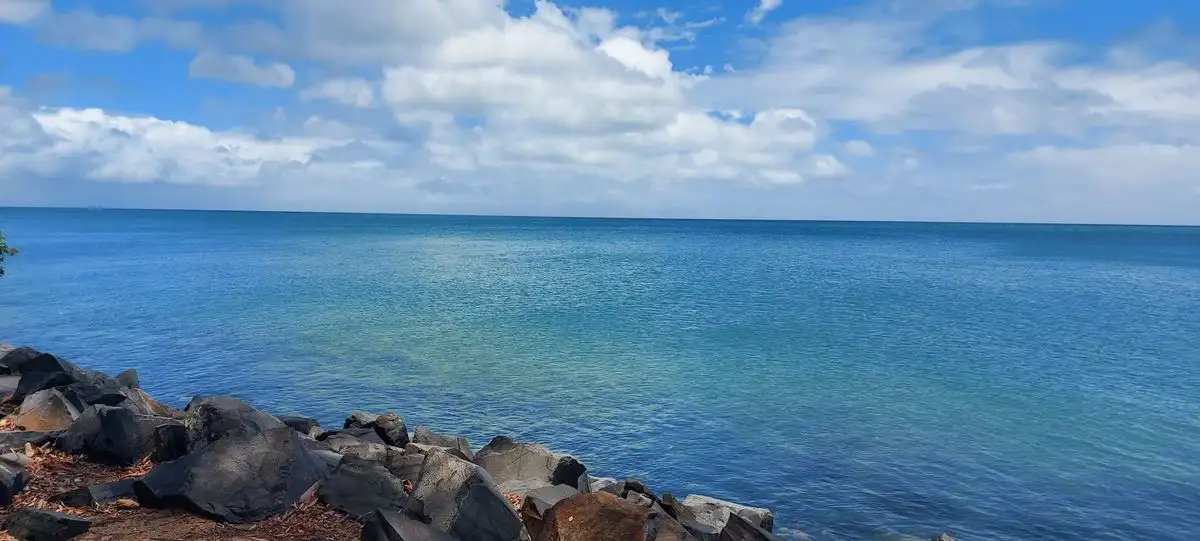 Calm water and a rocky shoreline at Hervey Bay under a clear blue sky
