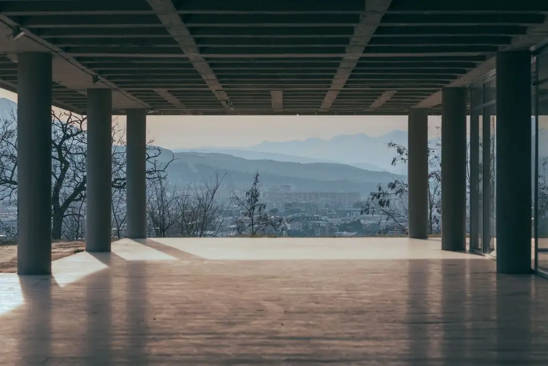Large open concrete floor under a roof, looking out to hills