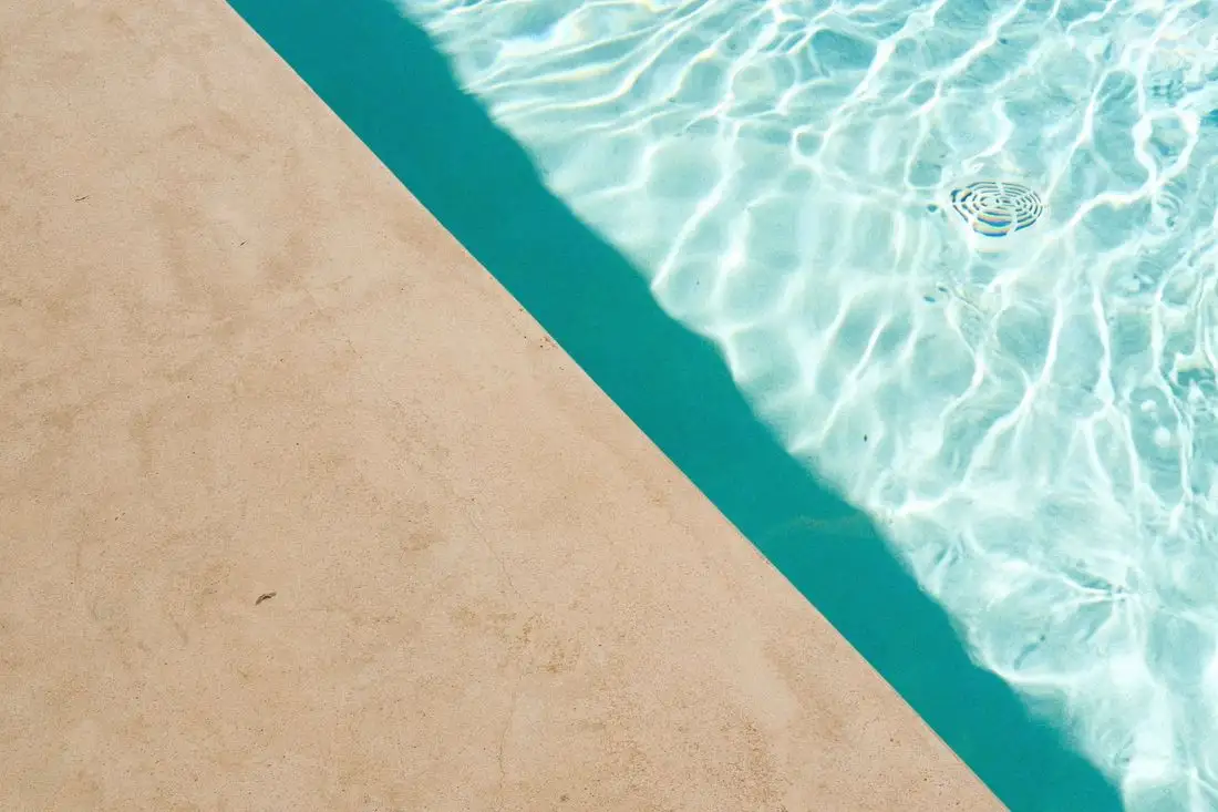 Pale concrete pool edge beside clear blue water